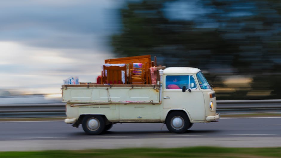 A white U-Haul moving truck with a large rectangular cargo area is parked outdoors on a paved surface, with the front windshield and side mirrors clearly visible. The cargo box is prominently displaye